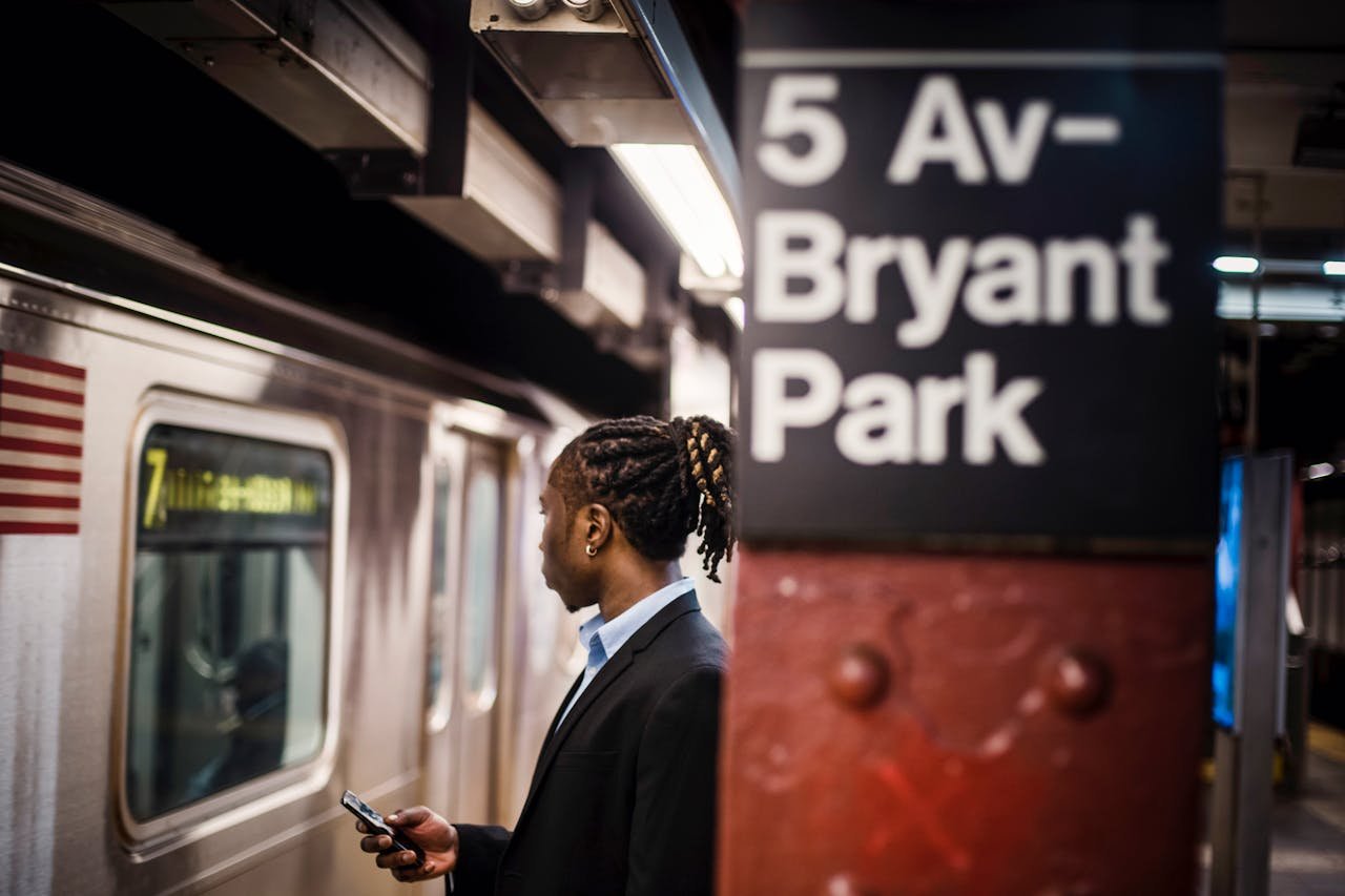 Elegant man with smartphone waiting for subway at Bryant Park in New York City.